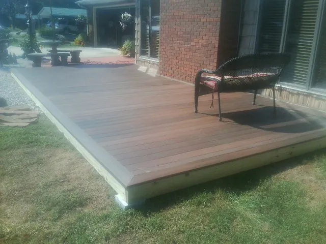 New wood deck and wicker chair beside a brick house in Conway